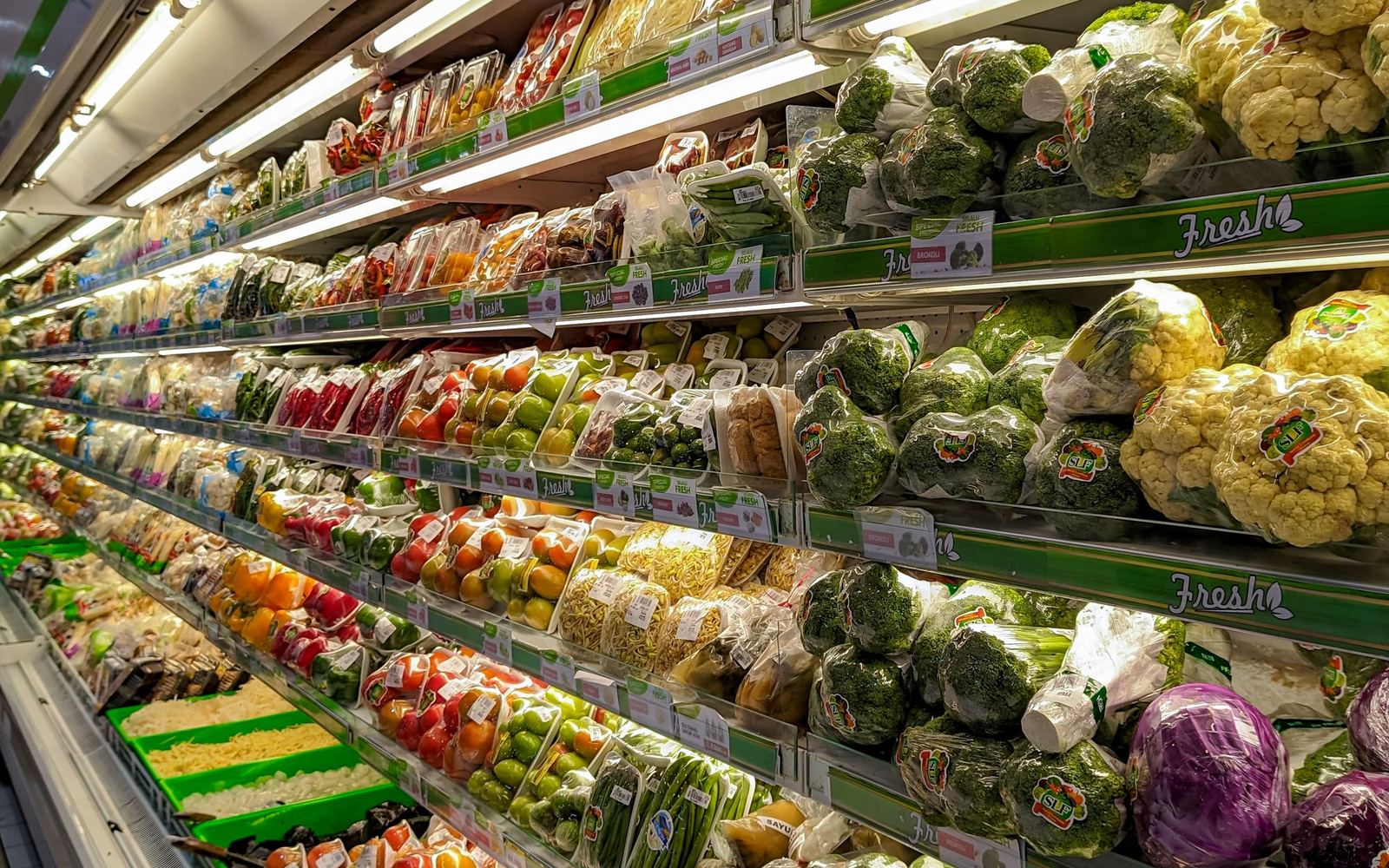 Gekoeld versschap in een supermarkt met rijen verpakte groenten en salades