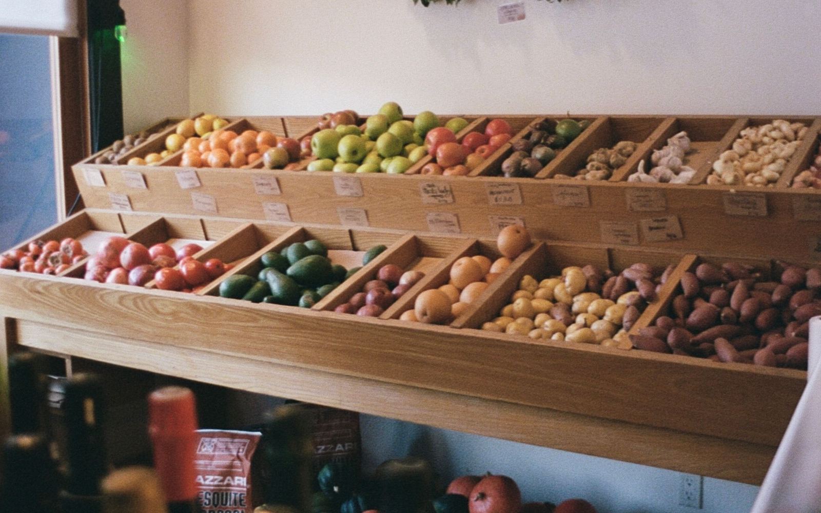Houten schappen en kistjes met groenten en fruit in het interieur van een kleine winkel bij daglicht